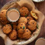 chana dal vada in a serving bowl on parchment paper, served with tea and coconut chutney.
