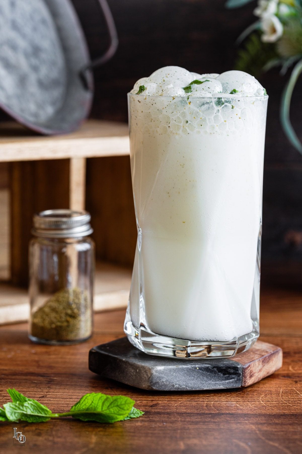 Soda chaas in a glass placed next to a small jar of ground spices.