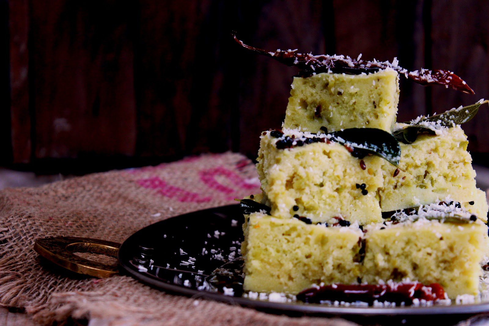 stack of Sooji Matar Dhokla garnished with desiccated coconut and dried red chilli