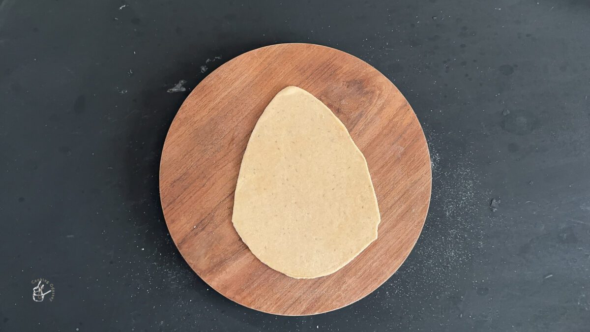 uncooked triangle ajwain paratha on a smooth working surface.