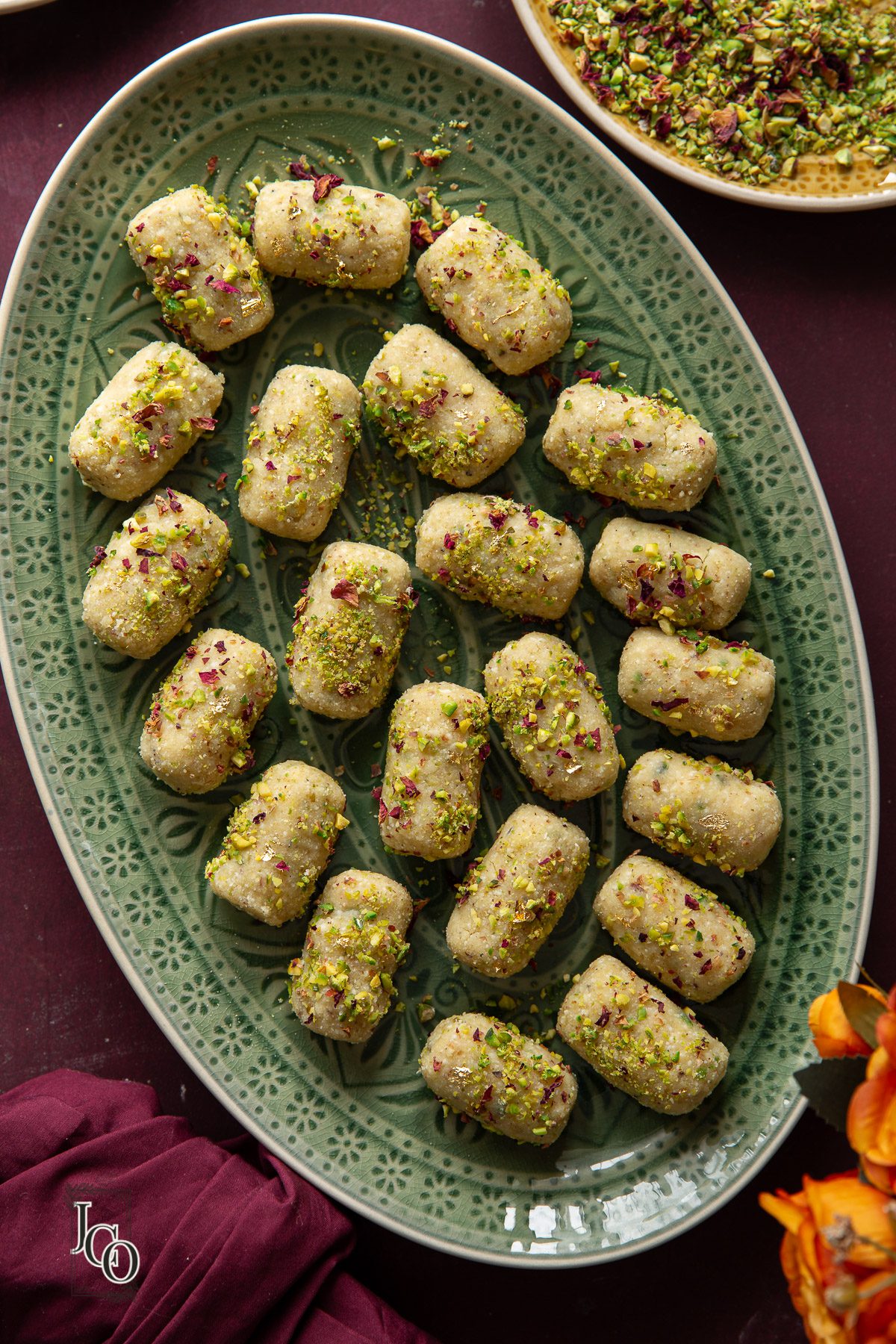 Indian sweet or mithai made with paneer and pistachio nuts arrabged in a serving dish.