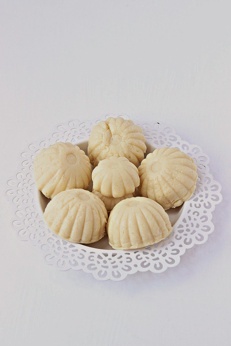 a small white plate filled with shaped cashew and paneer ladoos