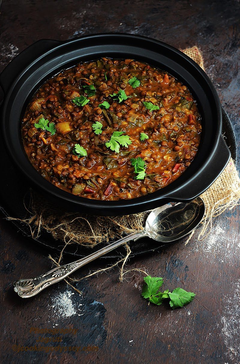 a black bowl filled with Puy Lentils and Swiss Chard Daal garnished with fresh coriander leaves