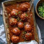 A serving dish filled with veg manchurian and garnished with chopped spring onion greens.