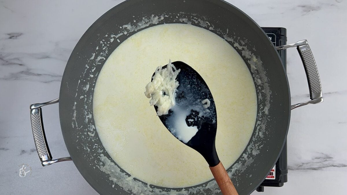 A female showing cooked rice on the spatula for dudhpak