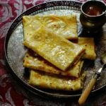 Folded Mande roti served in a big plate next to a bowl of vegetable curry