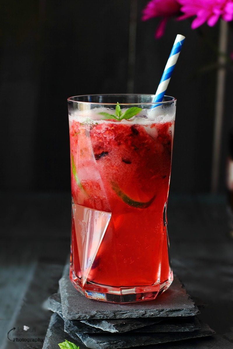 Virgin Mixed Berry Caipirinha served in a tall glass with a paper straw
