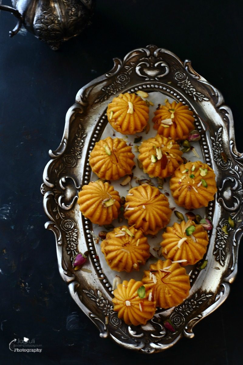 an oval tray with many kesar ladoos garnished with nuts