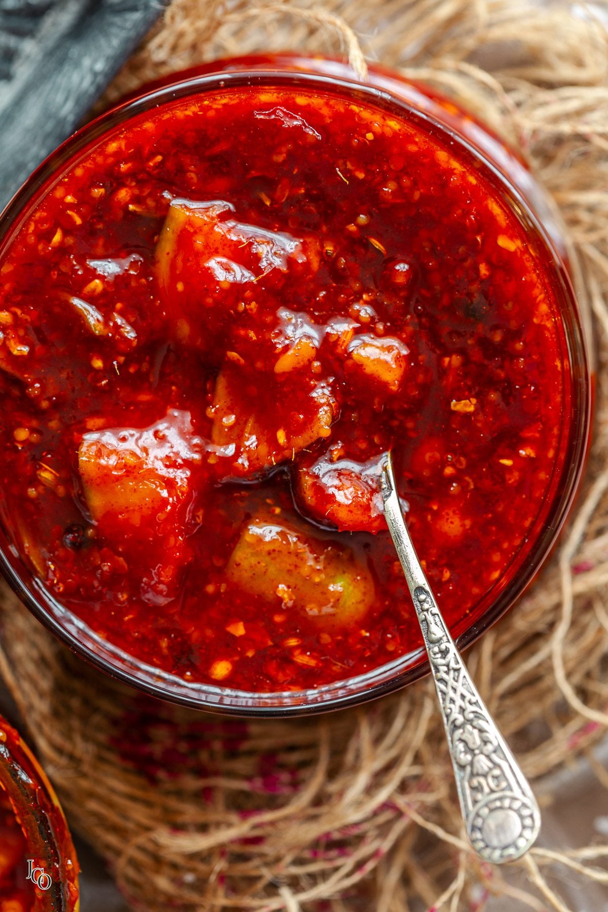 A close up of gor keri pickle in a clear glass jar with a spoon.