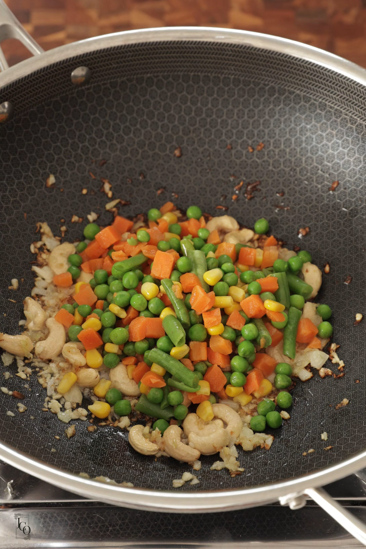 Mixed veggies like carrots, peas and green beans added to cooked onions.
