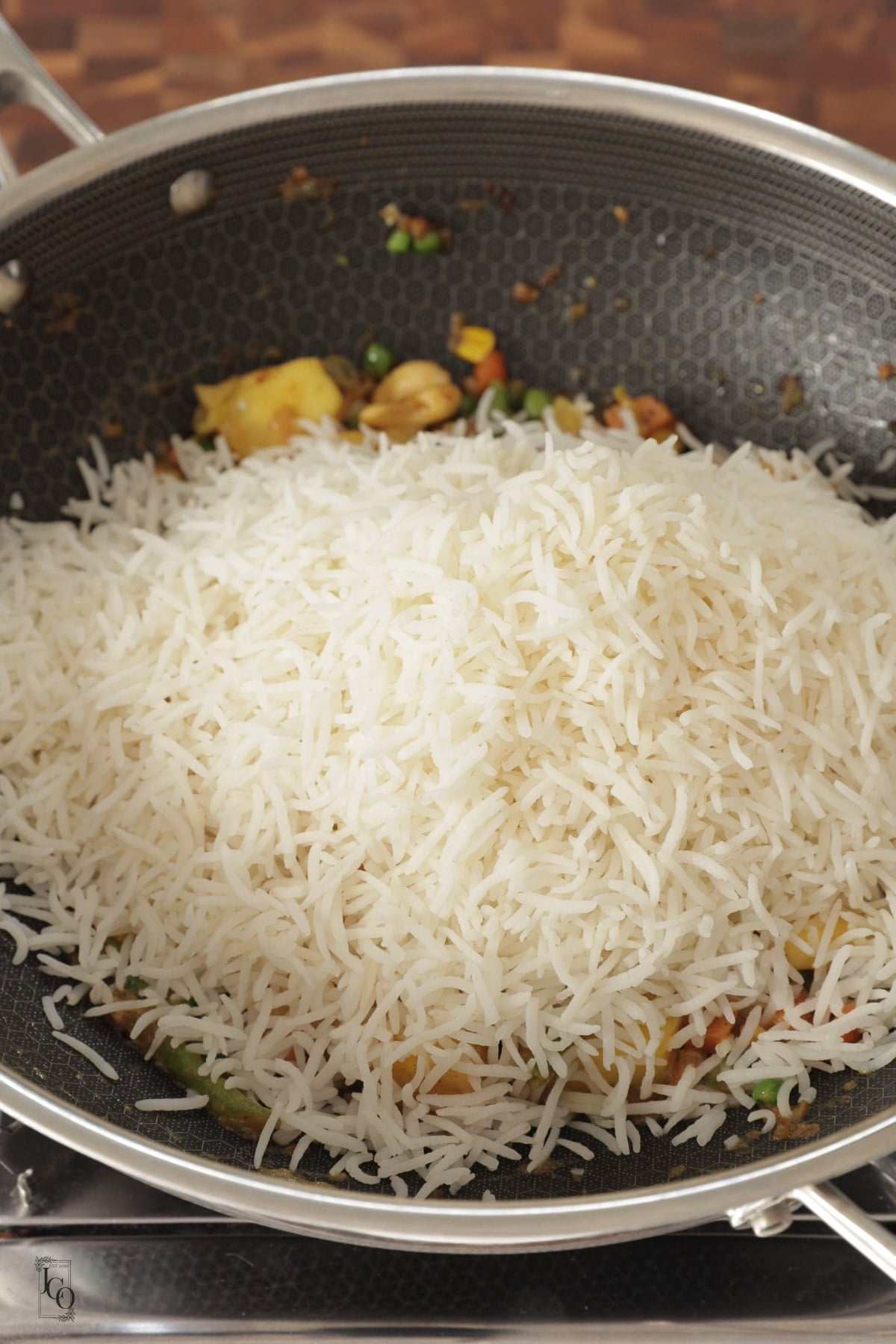 Cooked fluffy every grain seperated rice added to cooked mixed veg mixture.