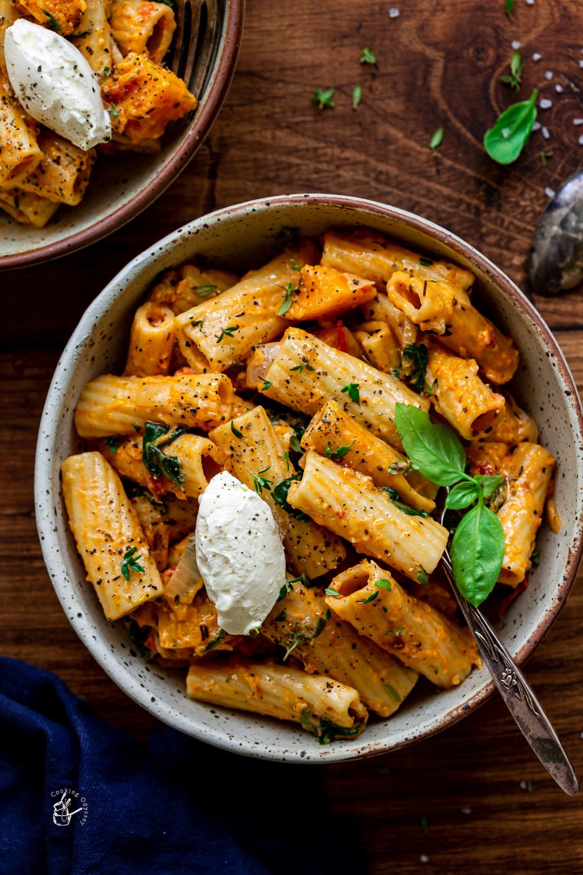 pumpkin pasta served in a bowl topped with some cheese and fresh herbs