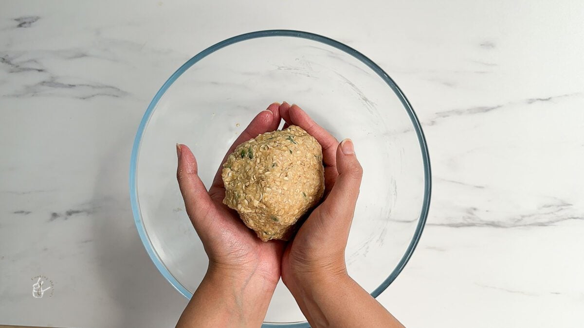 female hands are holding thyme oatcakes dough