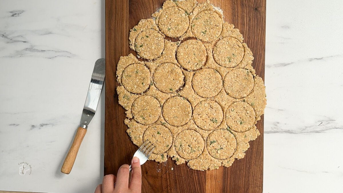 a female hand is pricking oatcakes using a fork