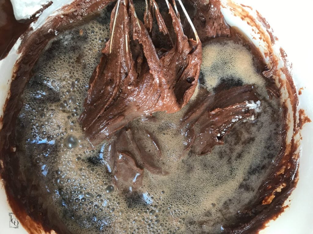 Coca cola added to the raw brownie batter in a bowl.