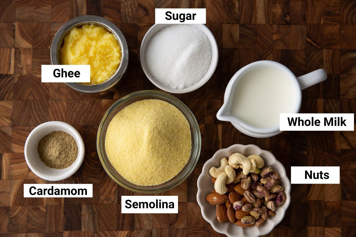 Semolina, sugar, ghee, milk and nuts in small bowls.