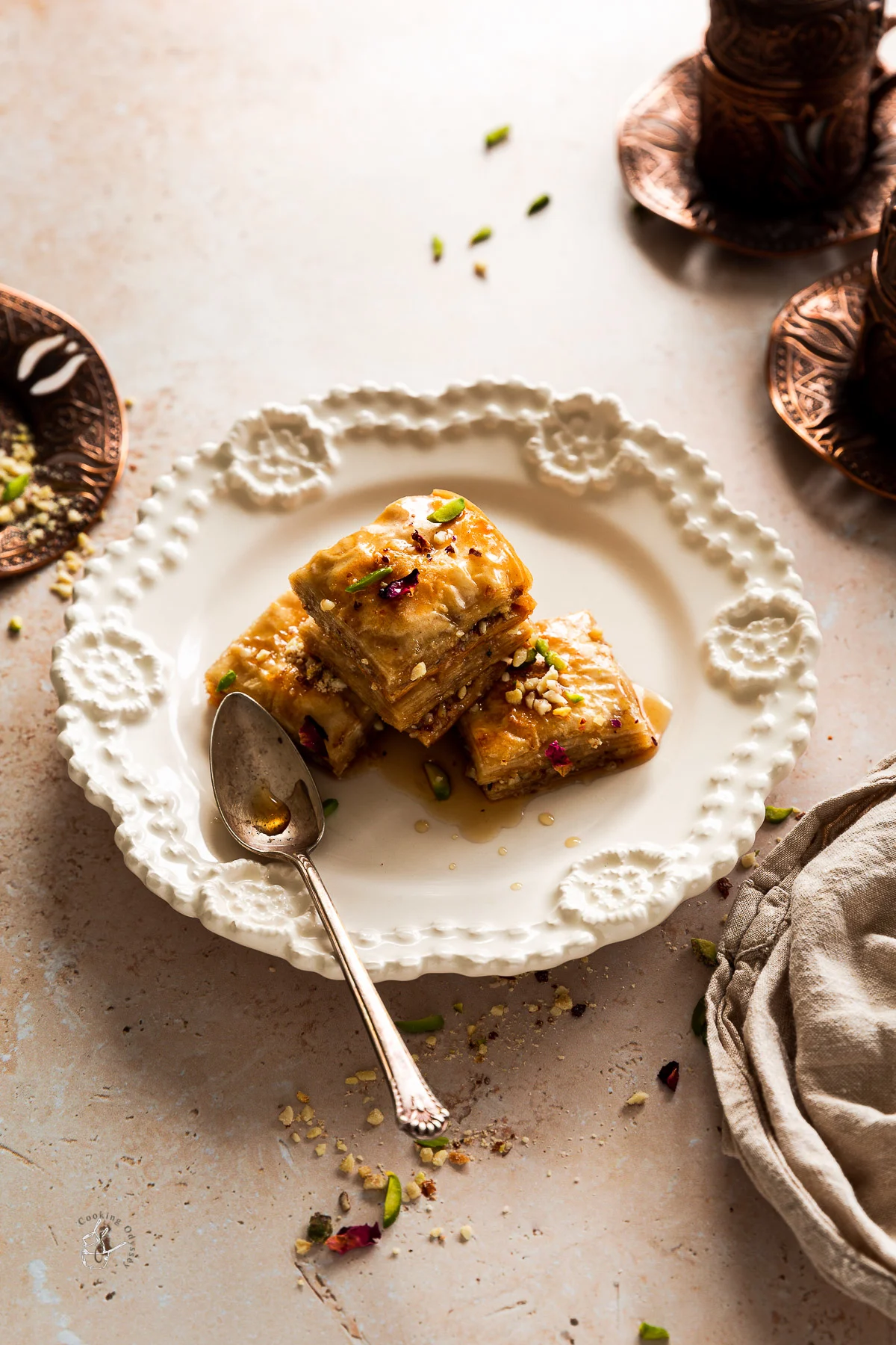 three baklava pieces served with coffee on a plate with a spoon