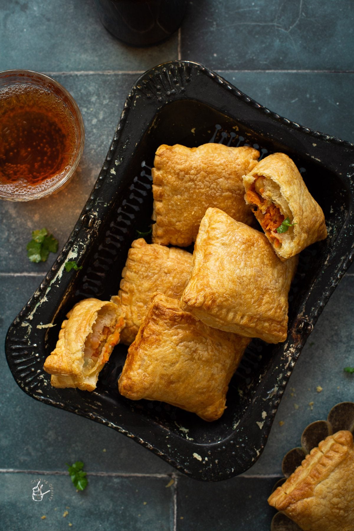Vegan curry puffs served on a plate next to soft drink glass