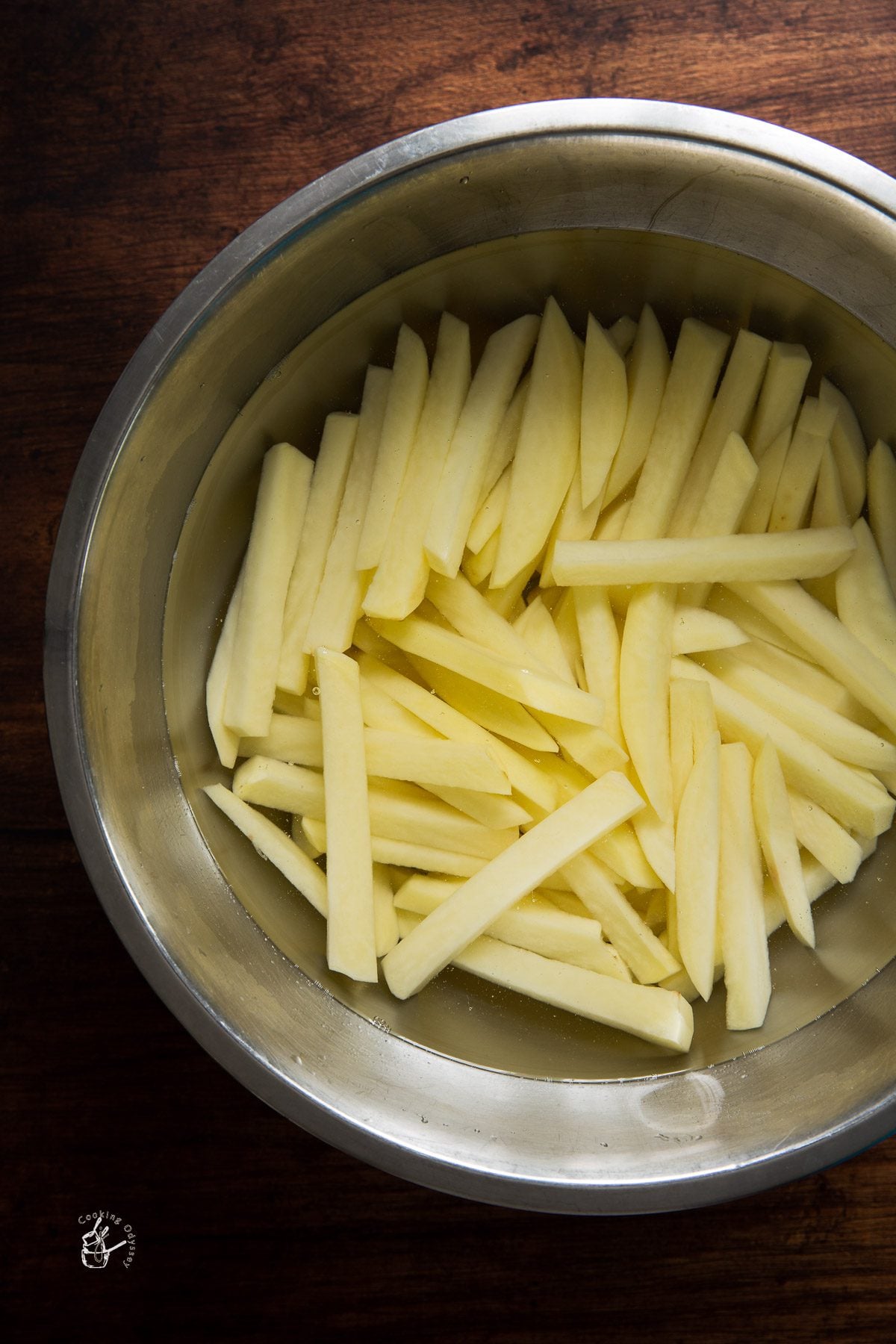 raw potato french fries in cold water bowl