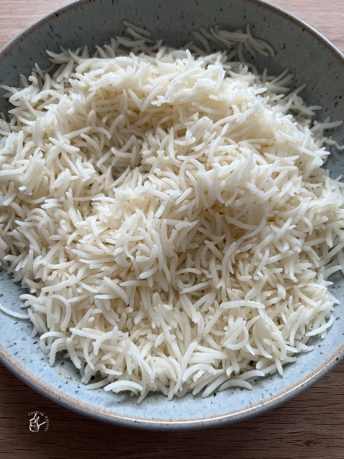 Cooked fluffy basmati rice in blue bowl. 