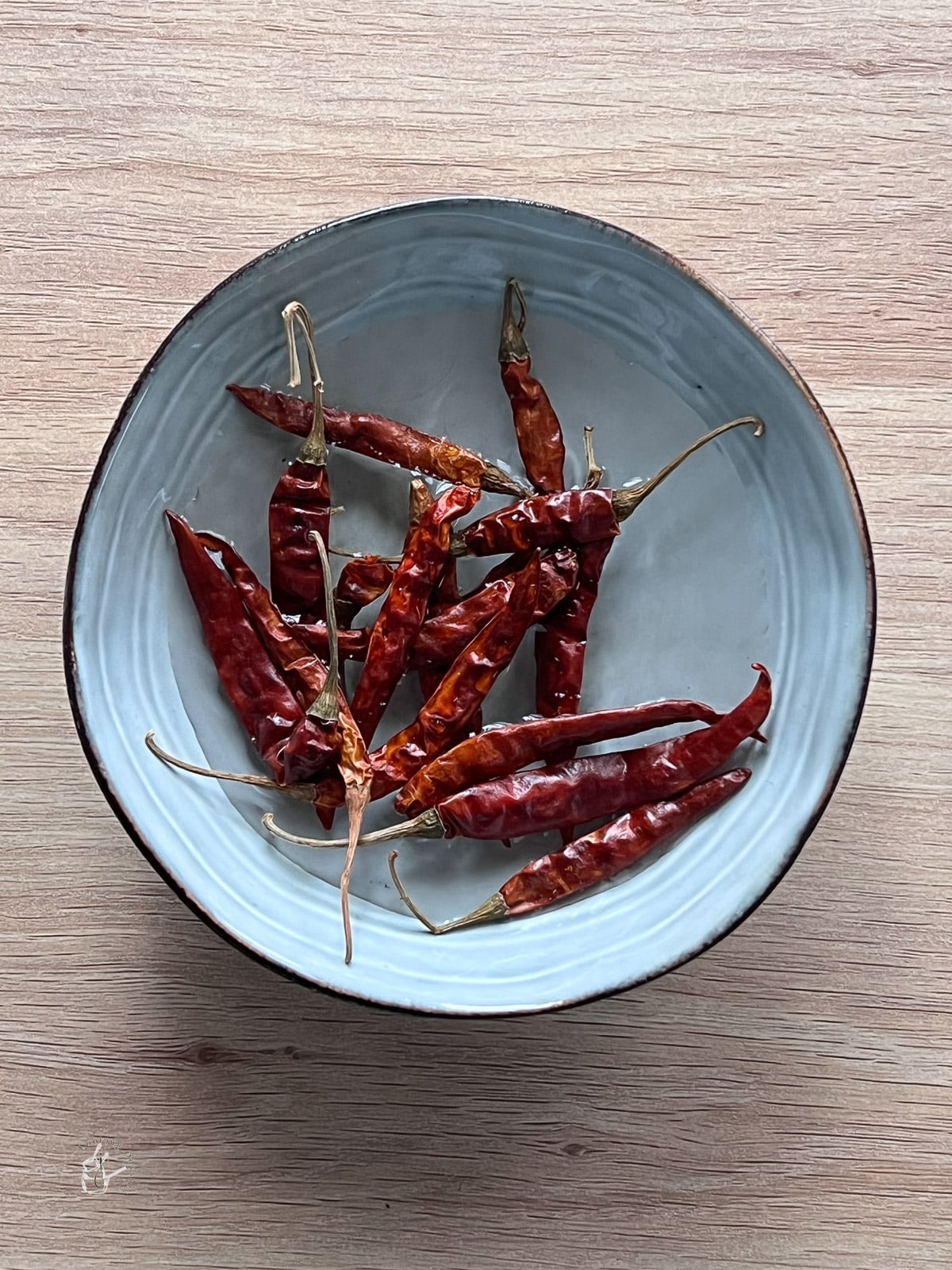 Dried red chillies soaking in water in a bowl. 