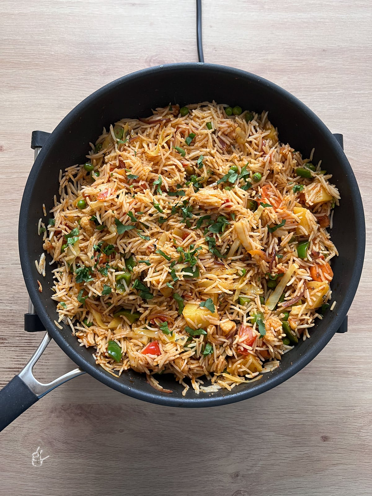 Chopped coriander sprinkled on tawa pulao in a pan. 