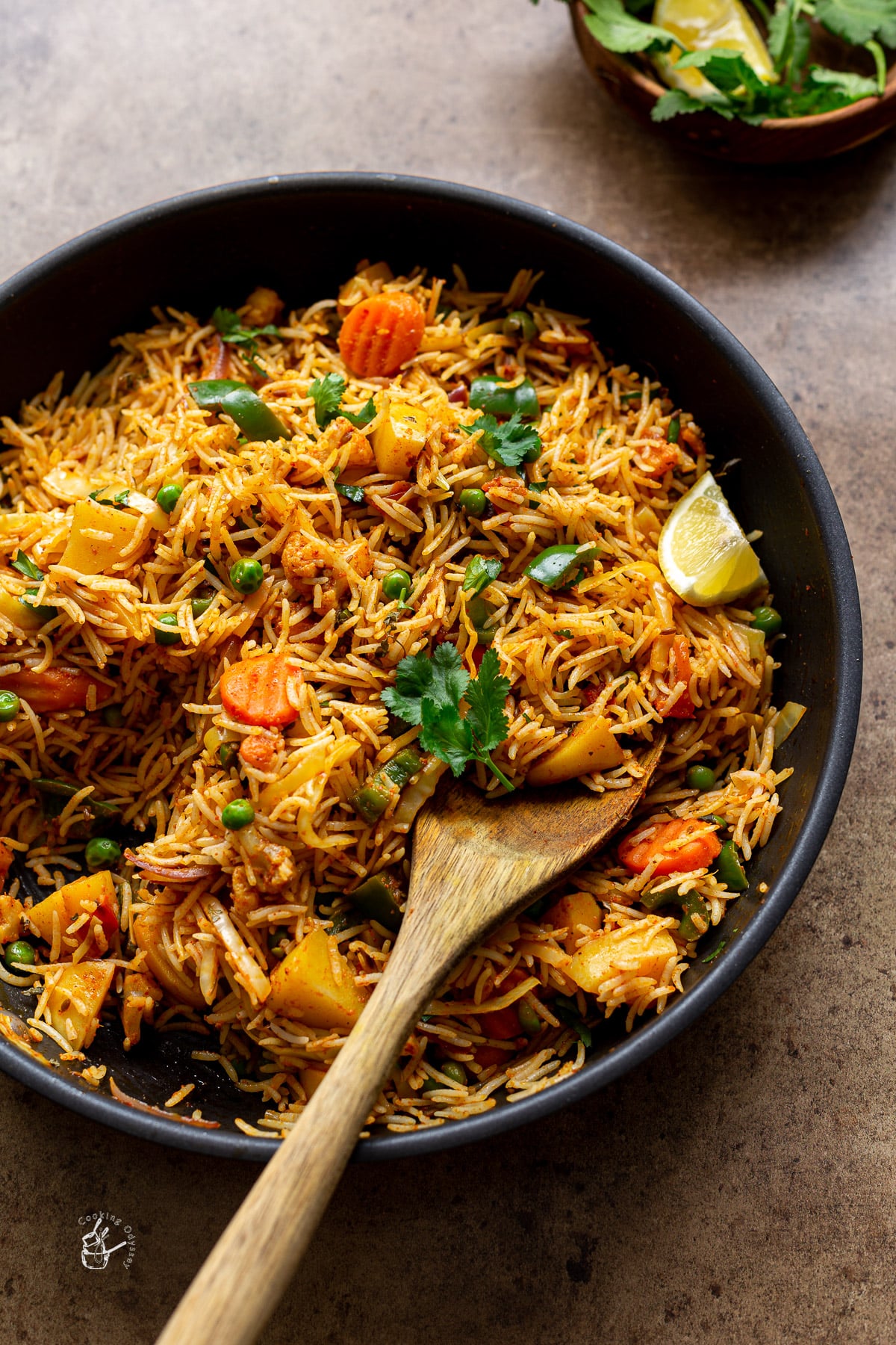 Tawa pulao with fluffy rice grains and vegetables in a pan with serving spoon.