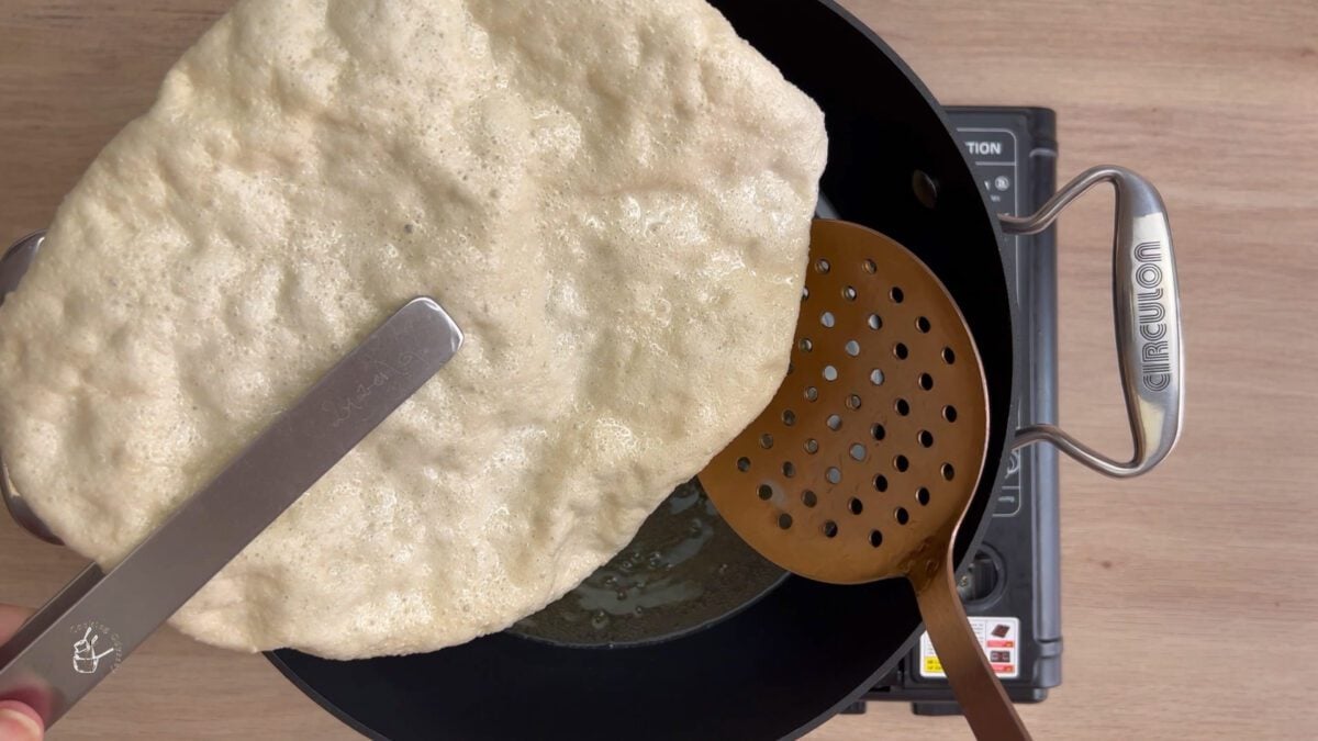 poppadum removed from the oil using kitchen tong 