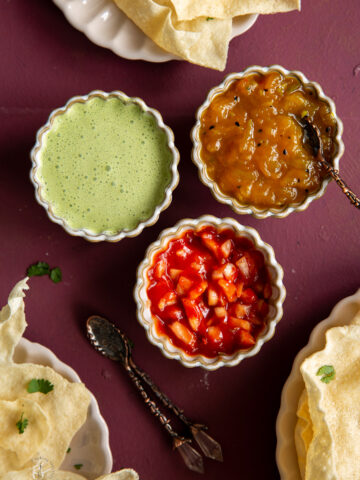 Three poppadom dips or Indian condiments served with fried poppadums on a table