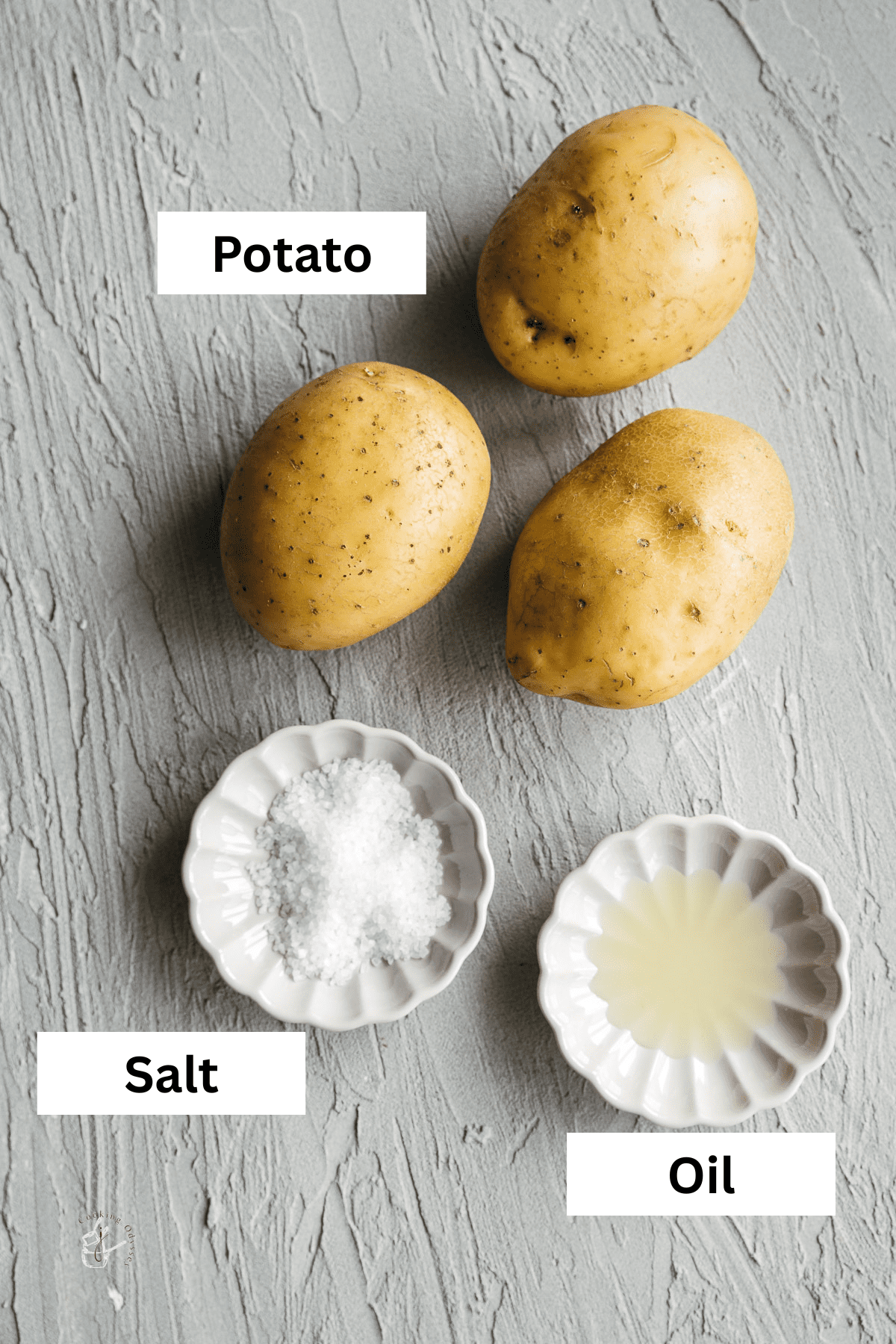 Ingredients like raw potatoes, oil and sea salt in bowls, placed on a grey backdrop.