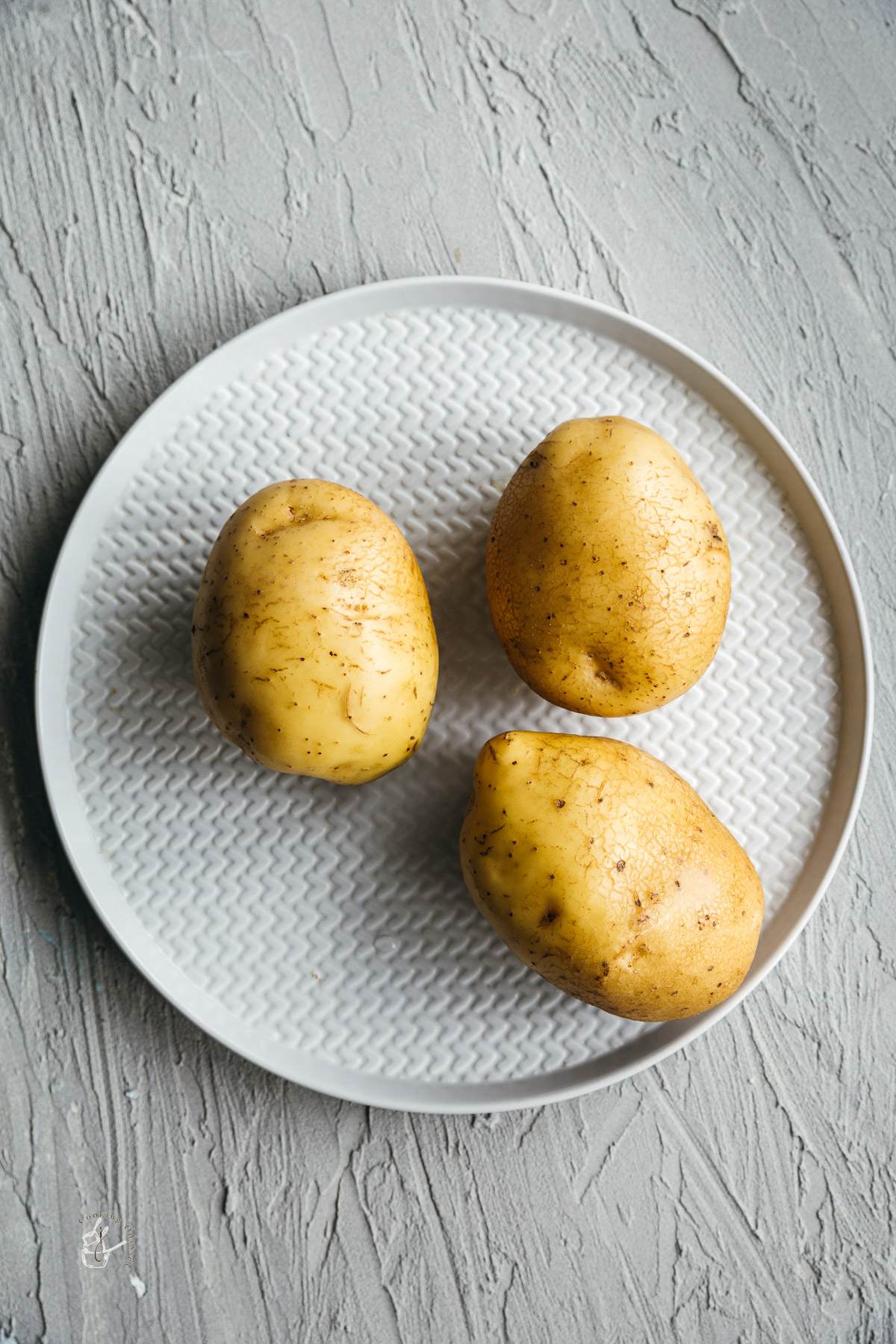 three cleaned and washed potatoes in a plate 