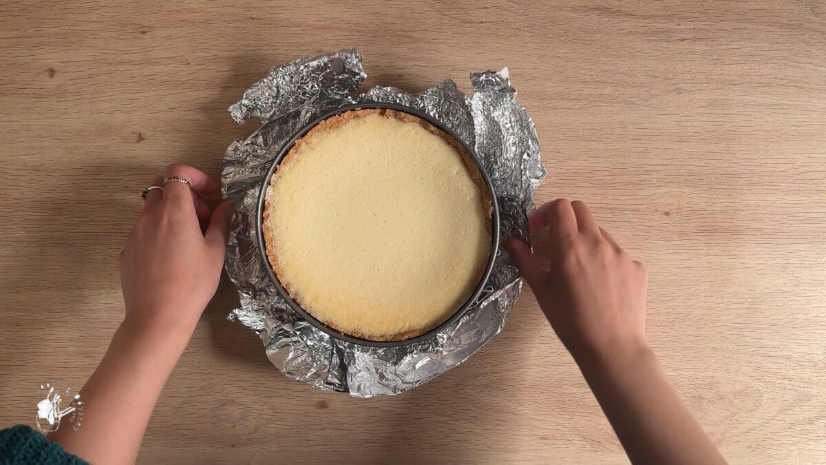 a female hands are removing tin foil from the cake tin