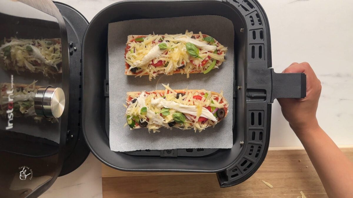 Two uncooked french bread pizza slices in the air fryer basket