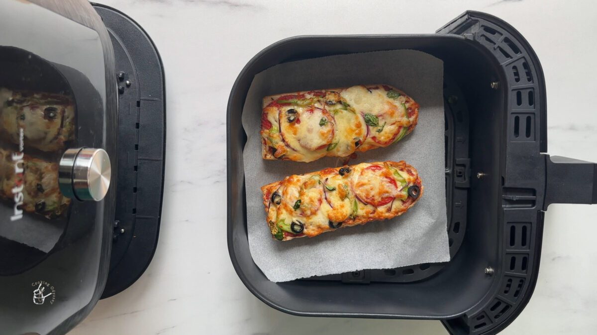 Two cooked bread pizza in air fryer basket