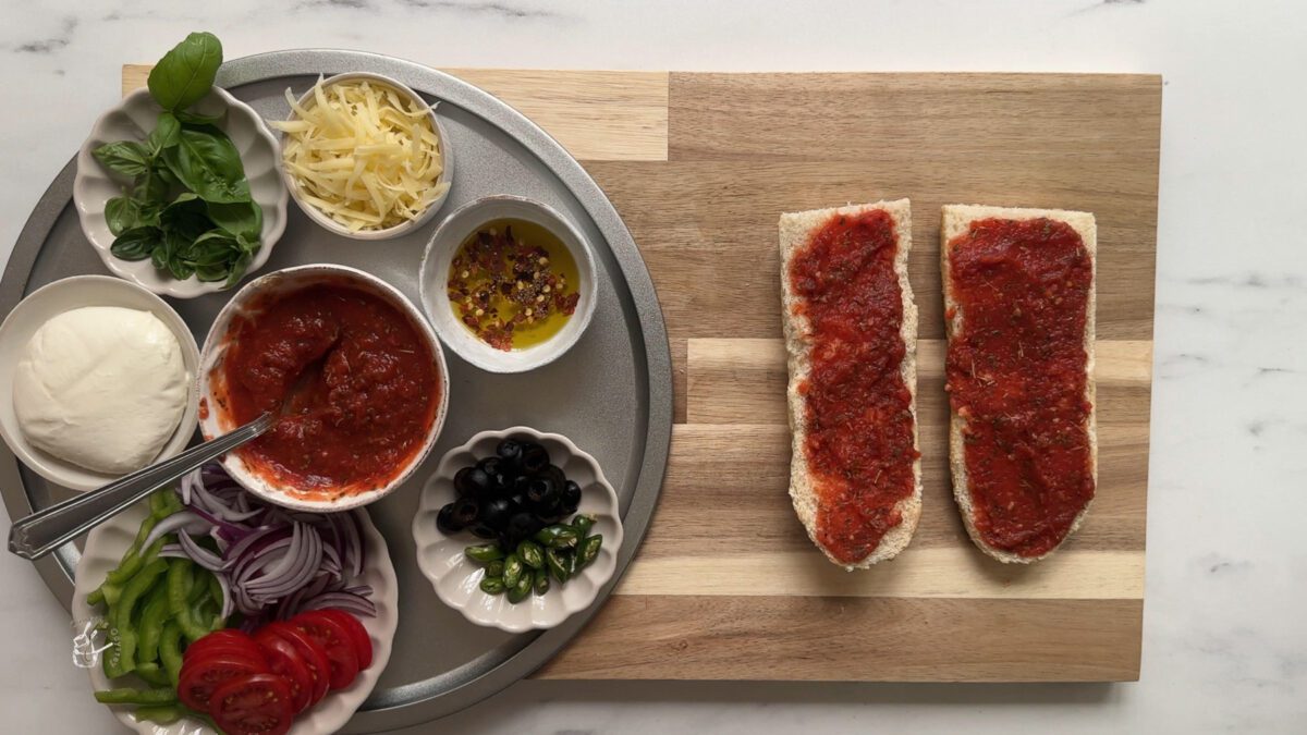 pizza sauce spread on two slices of french bread