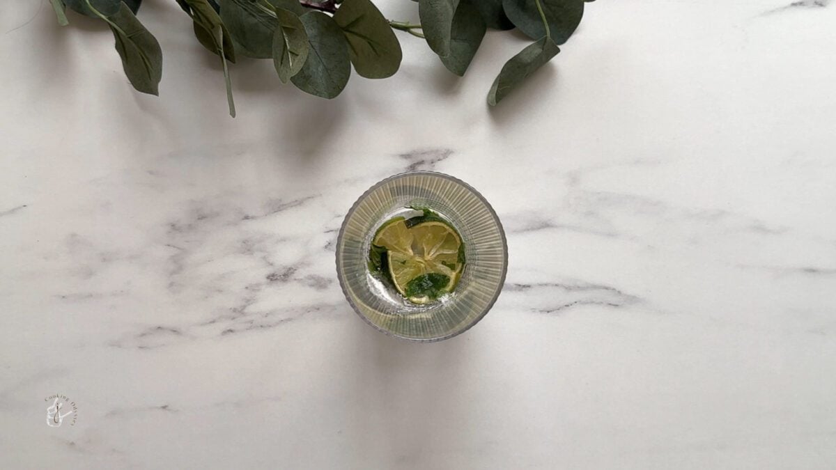 in a glass lime, mint and sugar are muddled 