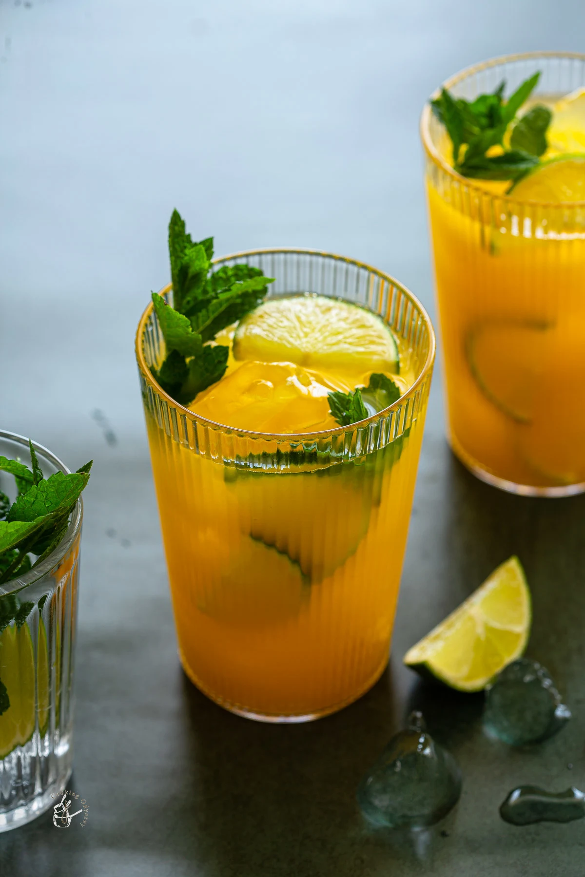 two glasses of mango mocktail on a green backdrop