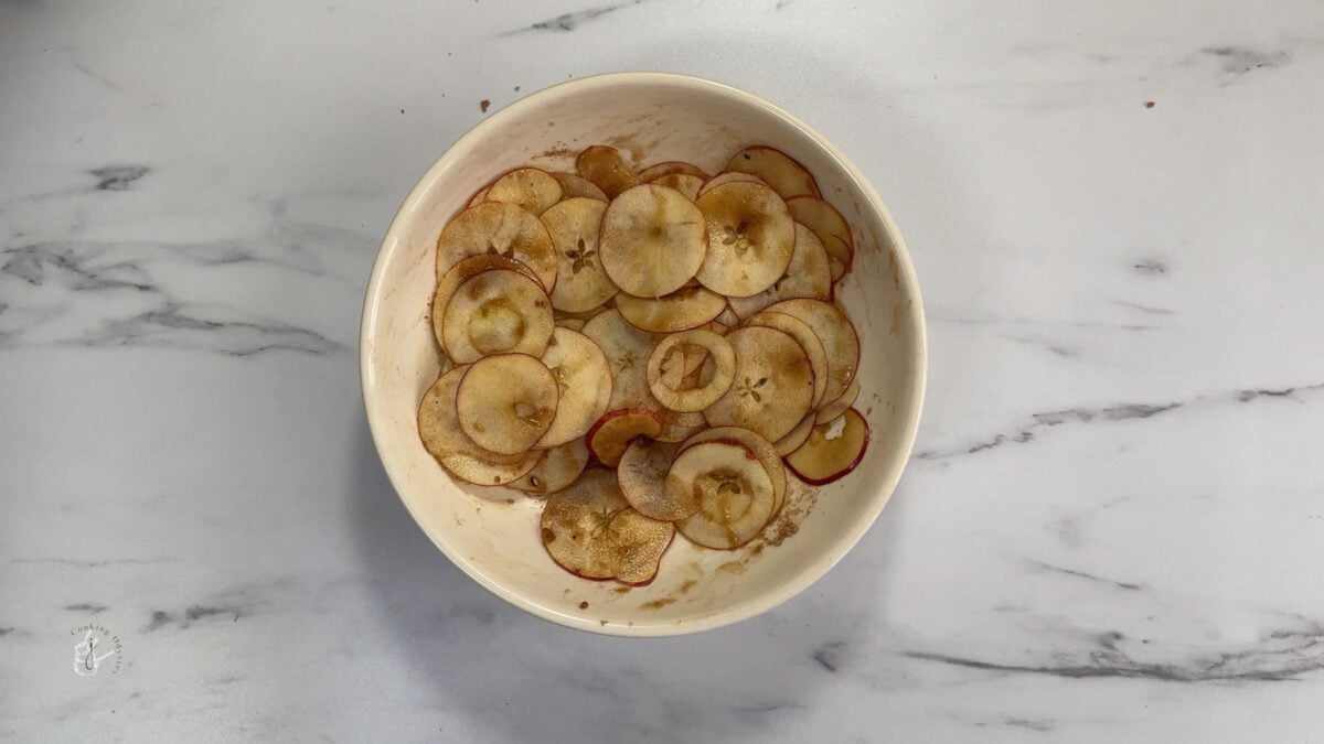 Sugar and apple sliced mixed in a bowl
