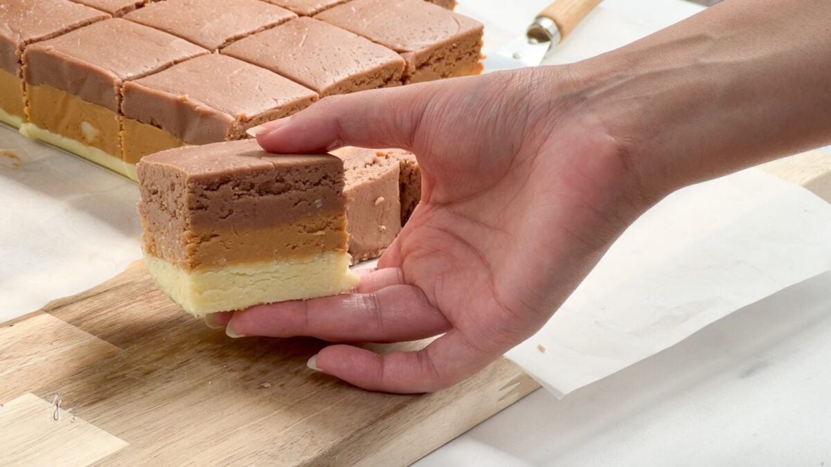 a female hand is holding a piece of Vanilla Caramel and Chocolate Barfi