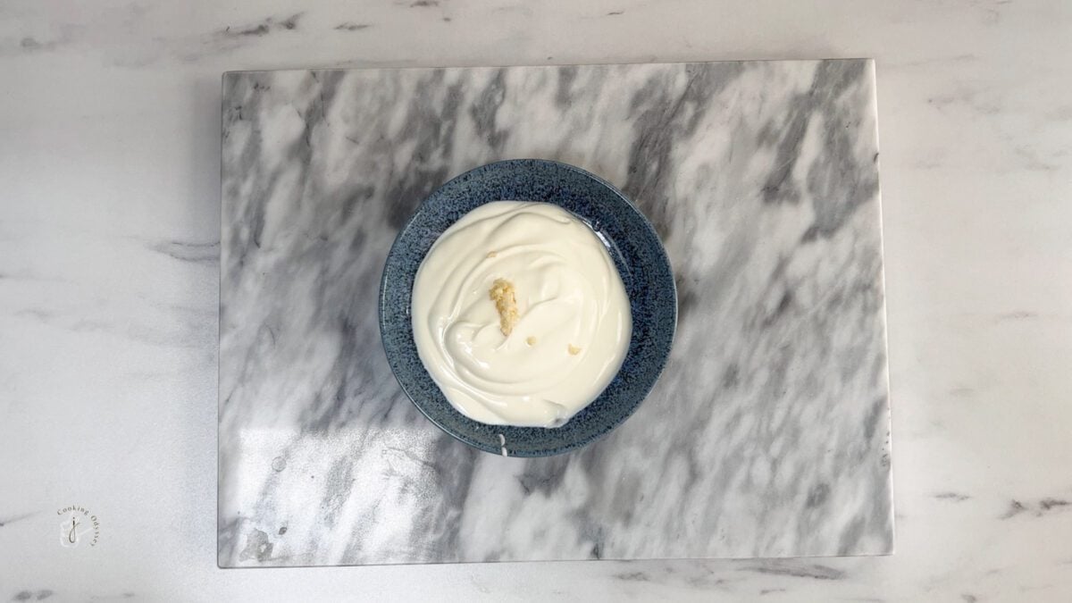 minced garlic added to the plain yogurt in a bowl