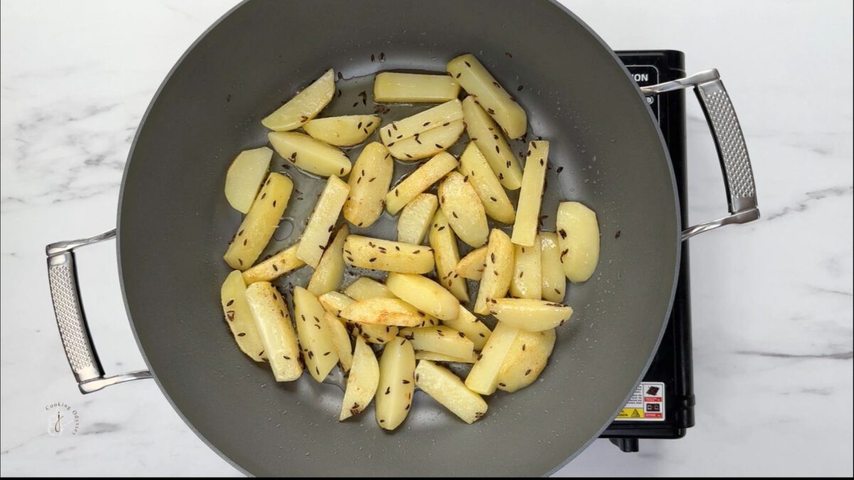 80 percent cooked potatoes are in the pan for aloo capsicum sabzi recipe
