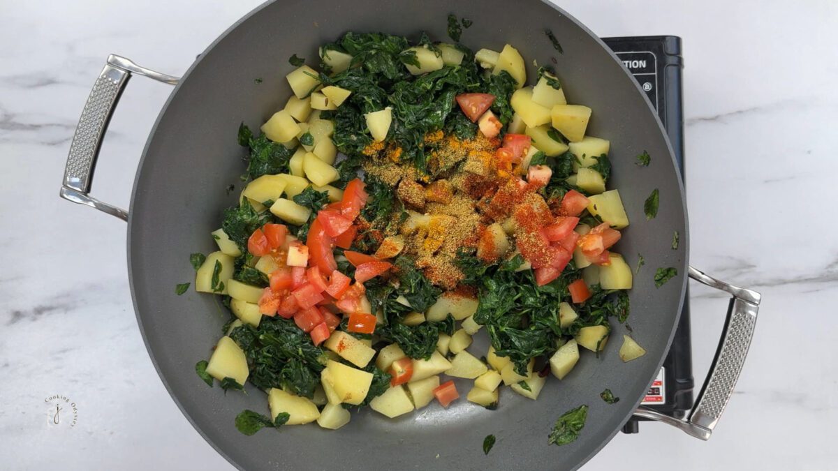 chopped fresh tomatoes and spices added to the wilted methi and potatoes 