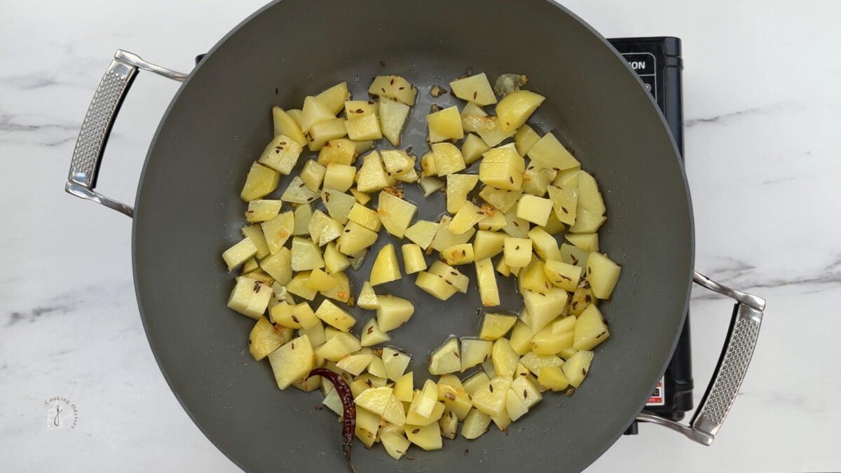 Half cooked potatoes in the pan for the recipe for alu methi