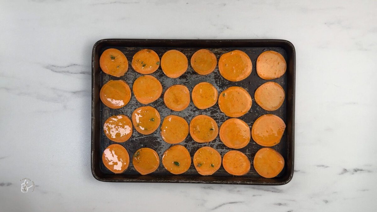 sweet potato slices brushed with orange and thyme oil in the baking tray