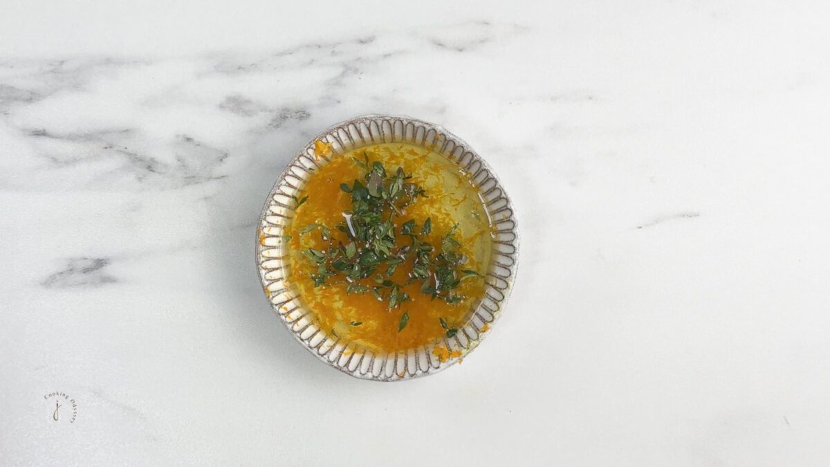 fresh thyme, orange zest and seasoning added to the olive oil in a small bowl