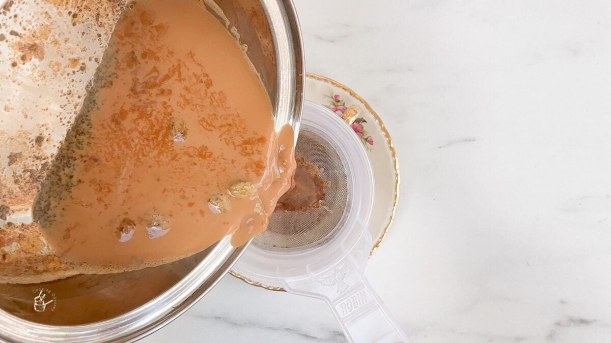 cardamom chai is being straind using a tea strainer