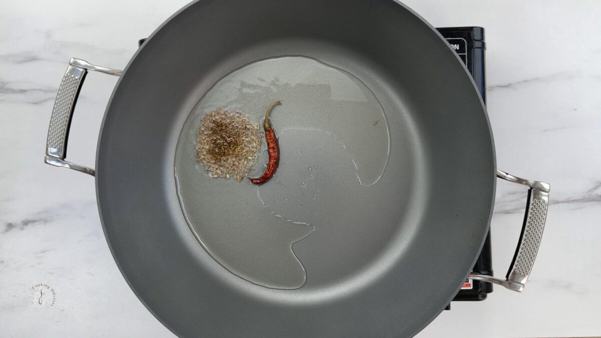 In hot oil cumin seeds, dried red chilli and hing added to the pan to make aloo methi