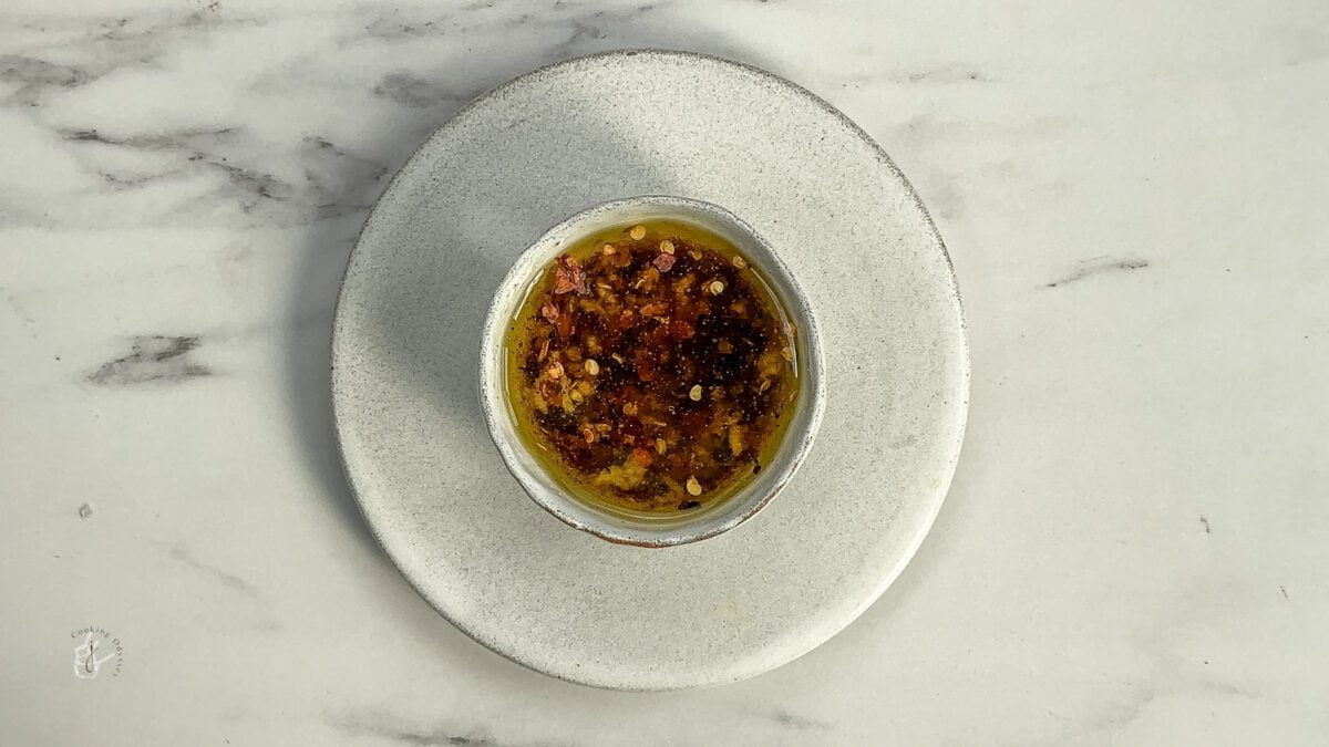a bowl of balsamic vinegar olive oil bread dip placed on the small plate