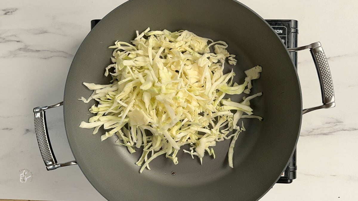 shredded cabbage added to the hot oil in the pan