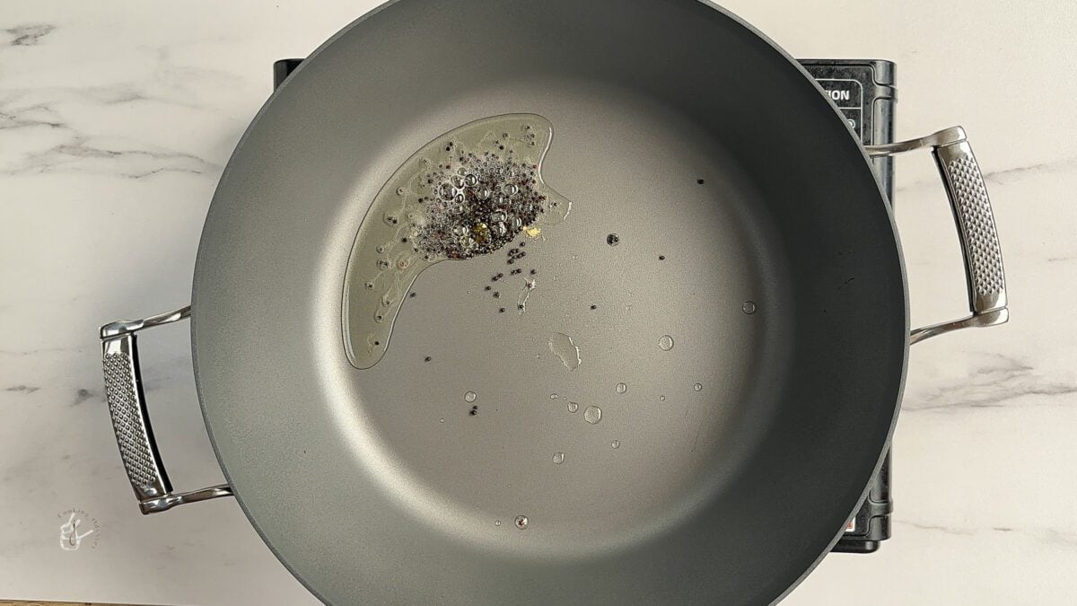 mustard seeds and hing added to the hot oil in the pan to prepare indian cabbge curry